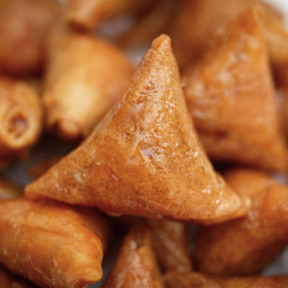 Close-up of triangular fried snacks with a glossy finish